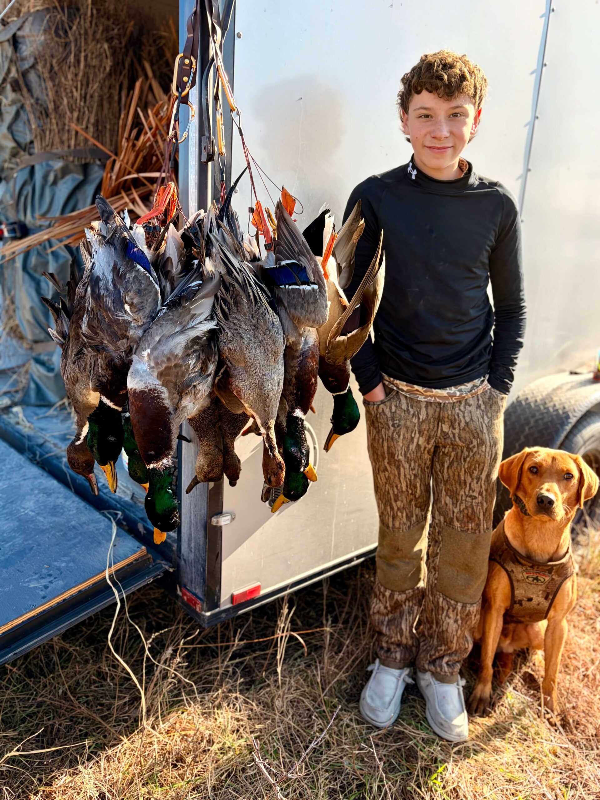 young hunter and a retriever dog beside a duck harvest